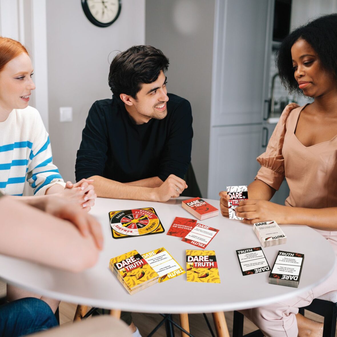 Cheerful multiethnic young friends gathered together, laughing at funny joke sitting at circle table in living room. Portrait of multicultural people having fun